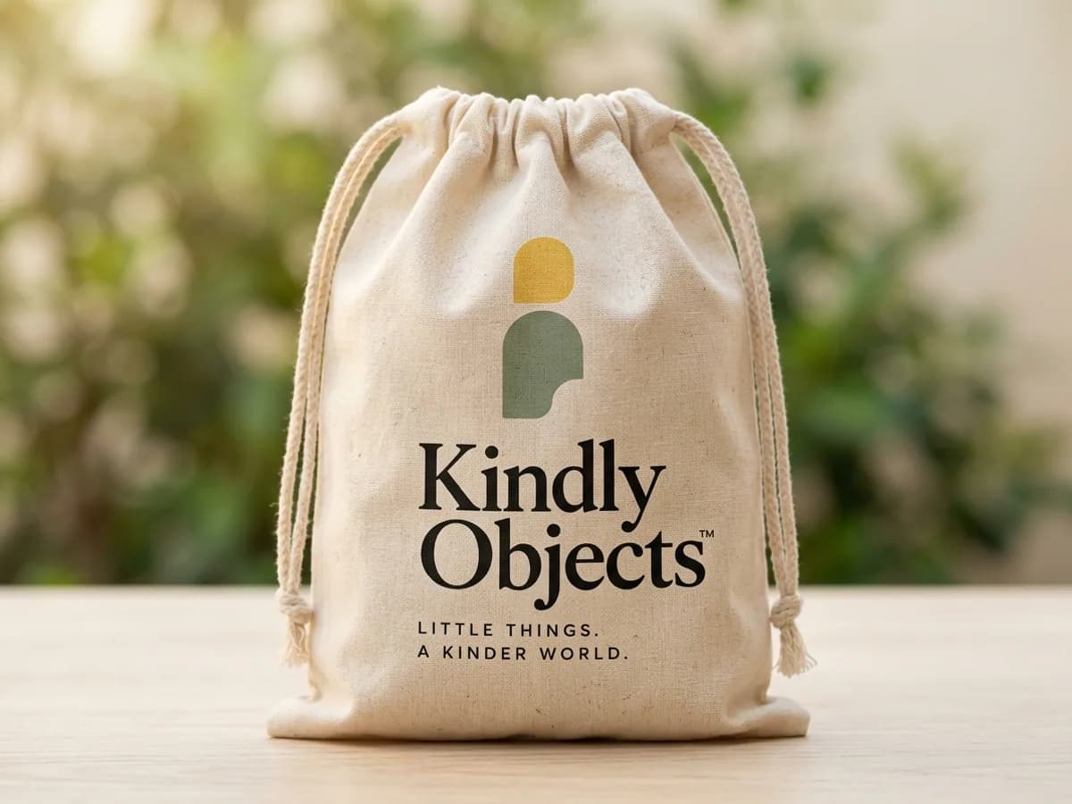 Natural cotton drawstring pouch printed with the Kindly Objects icon and wordmark — AI concept render
